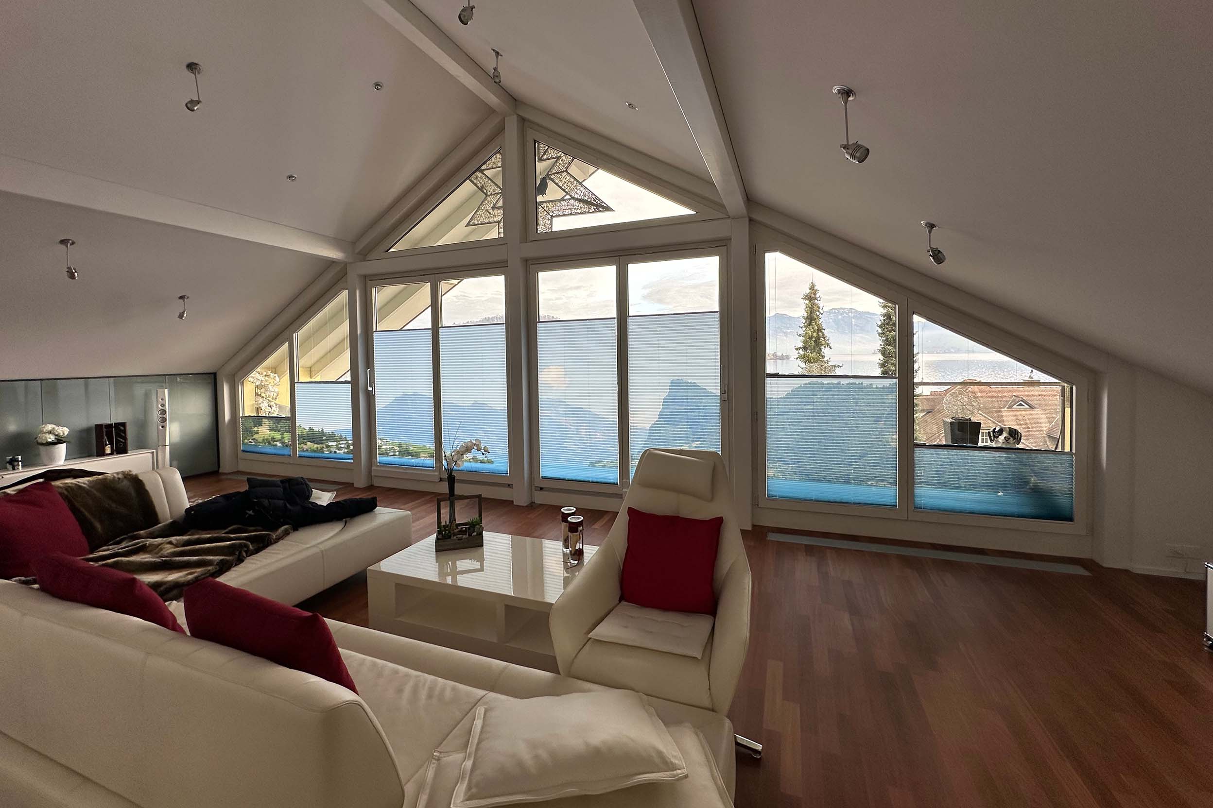 halb geöffnete Plissees an einer dreickgigen, vollflächigen Fensterfront